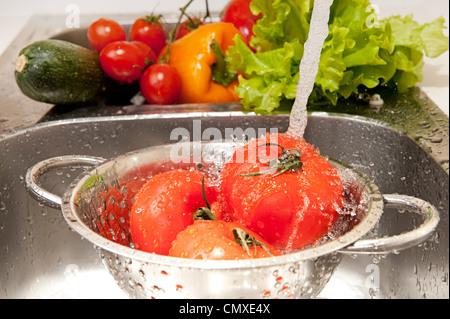 Trois tomates fraîches dans une passoire splashing in water Banque D'Images