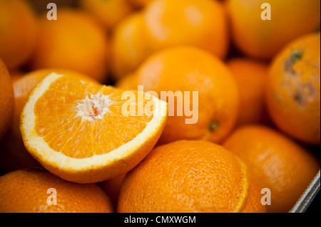 La moitié d'orange juteuse, tandis que d'autres ensemble des oranges sont flous en arrière-plan. Banque D'Images