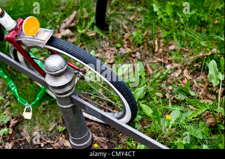 Une photo d'un vélo attaché à un poteau près de l'herbe. Banque D'Images