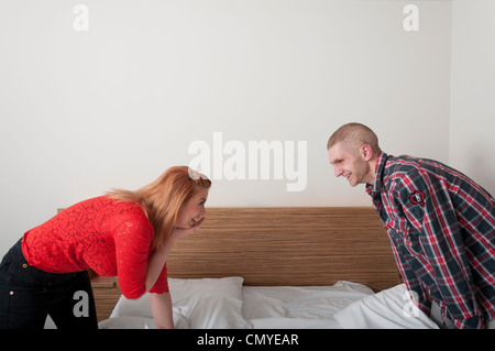 Young couple having pillow fight ludique dans chambre d'hôtel. Banque D'Images