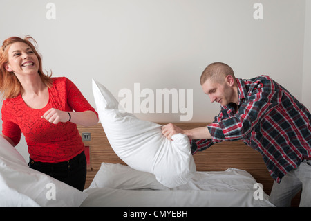Young couple having pillow fight ludique dans chambre d'hôtel. Banque D'Images