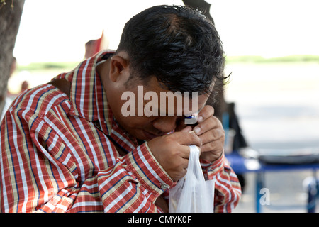 Un amateur d'une recherche dans l'amulette (marché Bangkok - Thaïlande). Un amateur d'amulettes sur le marché spécialisé de Bangkok. Banque D'Images