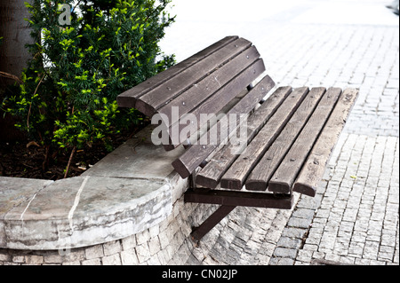 Plan de profil d'un trottoir en bois, vide - banc en face d'un buisson. Banque D'Images