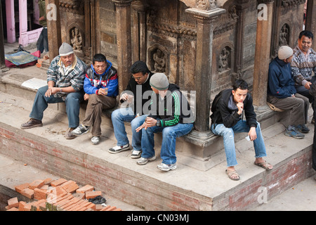 Les hommes se reposer et boire le chai à Bhimeleshvara Temple à Durbar Square - Katmandou, Zone Bagmati, Vallée de Katmandou, Népal Banque D'Images