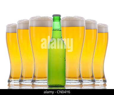 Une bouteille de bière verte debout devant six verres frosty froid mousseux avec des hauts. Banque D'Images