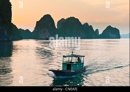 Bateau de pêche au coucher du soleil, la baie d'Ha Long, la baie d'Halong. UNESCO World Heritage Site. Vietnam Banque D'Images