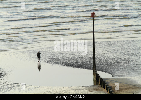 Une figure solitaire reflète dans piscine de l'eau sur la plage d'Eastbourne, East Sussex, Angleterre Banque D'Images