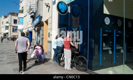 Un homme avec un vélo en prenant l'argent d'un distributeur automatique de la banque Barclays Hayes Cardiff Wales UK Banque D'Images