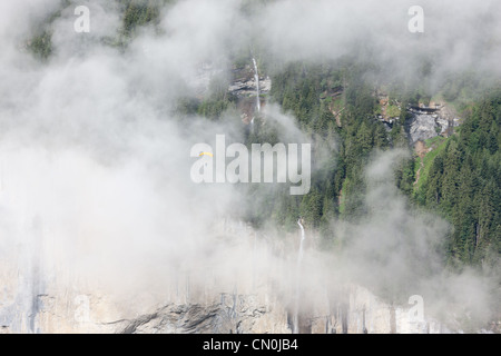 Parachutiste / parachutiste envoquant par une cascade enveloppée de brouillard.Staubbachfall, vallée de Lauterbrunnen, Berne, Suissland. Banque D'Images