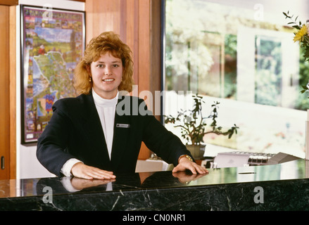 Une jeune femme souriante est employée à la réception de l'hôtel, Californie, USA 1990s Banque D'Images