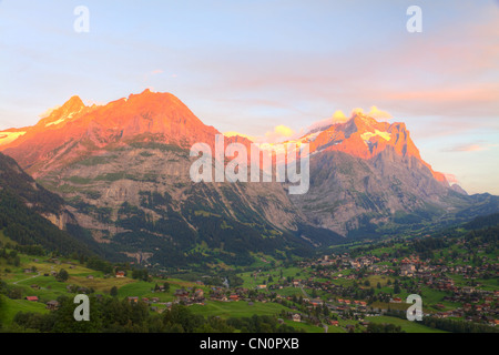 Alpenglow sur ville des Alpes dans la vallée de Grindelwald au coucher du soleil en face de montagnes Eiger north face, Suisse Banque D'Images