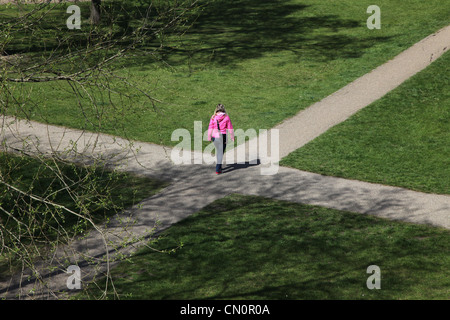 Femme à un carrefour junction dans un parc, de décider où aller. Banque D'Images