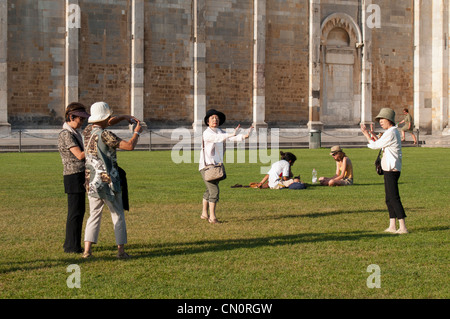 Des touristes posent pour des photos faisant semblant de retenir la Tour de Pise sur la Piazza dei Miracoli, Italie Banque D'Images