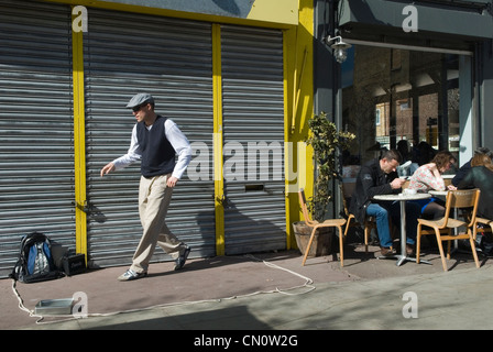 Hackney. Chatsworth Road. Homme faisant une danse de rue, il est busking, collecte de l'argent boîte de collecte de boîte à gauche de l'image. Les gens appréciant le café du dimanche matin assis à l'extérieur d'un café-bar. Ne payant aucun intérêt dans le busker des années 2012 2010 UK HOMER SYKES Banque D'Images