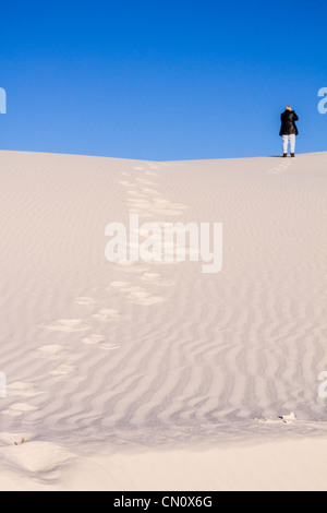 Photographe grimpant des dunes de sable au parc national de White Sands (anciennement Monument national) au Nouveau-Mexique, par une matinée froide en février. Banque D'Images