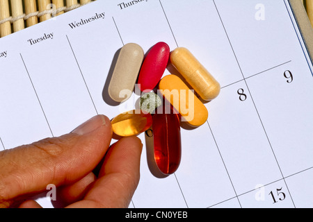 Vitamines et minéraux sur le calendrier avec les doigts jusqu'à en prendre un Banque D'Images