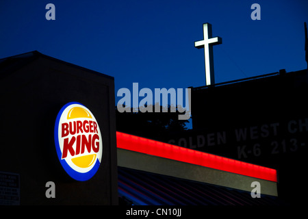 Burger King en néon avec de grandes croix de l'église en arrière-plan contre twilighjt sky Banque D'Images