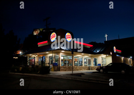 Extérieur nuit restaurant Burger King avec vue sur la croix de l'église et en arrière-plan Banque D'Images