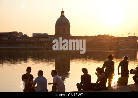 Les gens s'assoient sur les rives de la Garonne, au coucher du soleil à proximité de Dôme de la Grave, Toulouse, France Banque D'Images