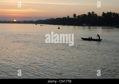 Bateau à rames traditionnelles sur la rivière au coucher du soleil. Pathein. Delta de l'Irrawaddy. Myamar. Banque D'Images