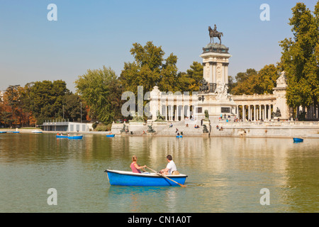 Madrid, Espagne. De l'aviron sur l'Estanque, ou d'un lac, dans les jardins d'El Retiro. Monument au roi Alphonse XII en arrière-plan. Banque D'Images