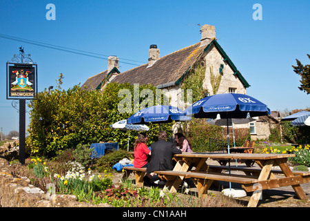 Les gens de parler dans un pub de jardin dans le soleil du printemps dans le Wiltshire, England, UK Banque D'Images