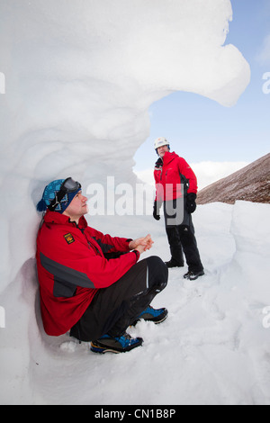 Les alpinistes à l'abri dans un trou à neige dans les montagnes de Cairngorm, Ecosse, Royaume-Uni. Banque D'Images