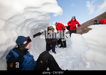 Les alpinistes à l'abri dans un trou à neige dans les montagnes de Cairngorm, Ecosse, Royaume-Uni. Banque D'Images