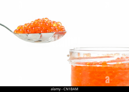 Caviar de saumon rouge sur une cuillère et un pot de verre sur un fond blanc Banque D'Images
