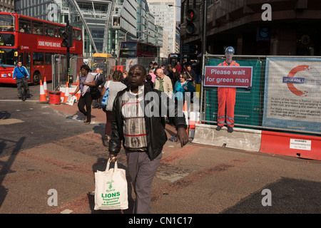 Jaywalker un homme s'arrête à mi-chemin à travers un carrefour sur une lumière rouge zone piétonne dans le centre de Londres au cours de l'amélioration des rues temporaires. Banque D'Images