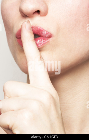 Femme tenant l'index à la bouche, faisant des gestes pour le silence Banque D'Images