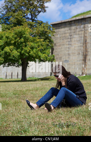 Woman Sitting on Grass Talking on Phone Banque D'Images