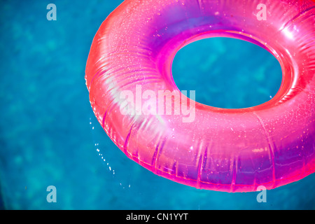 Jouets gonflables flottants à la piscine en été, éclairés par un soleil chaud Banque D'Images