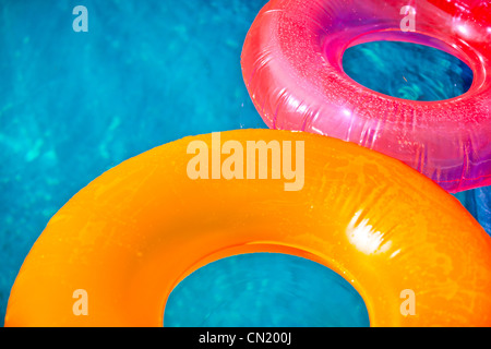 Jouets gonflables flottants à la piscine en été, éclairés par un soleil chaud Banque D'Images