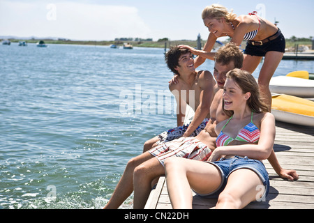 Deux jeunes couples assis sur le bord de la jetée s'Amusant Banque D'Images