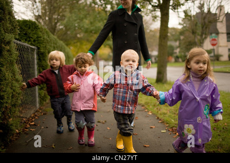 Femme avec quatre enfants marchant le long trottoir Banque D'Images