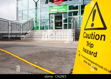 Un trébuchement signe par un tuyau flexible à l'extérieur de l'Asda Keighley, West Yorkshire, Royaume-Uni. Banque D'Images