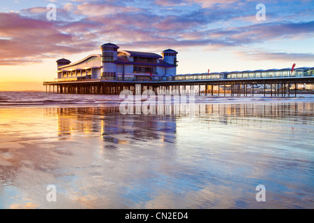 Coucher de soleil sur la grande jetée à Weston-Super-Mare, Somerset, England, UK compte dans le sable humide de la plage à marée haute. Banque D'Images