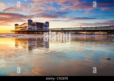 Coucher de soleil sur la grande jetée à Weston-Super-Mare, Somerset, England, UK compte dans le sable humide de la plage à marée haute. Banque D'Images