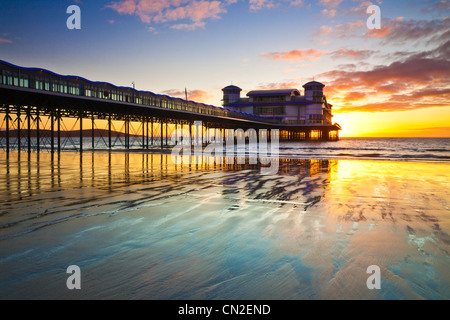 Coucher de soleil sur la grande jetée à Weston-Super-Mare, Somerset, England, UK compte dans le sable humide de la plage à marée haute. Banque D'Images