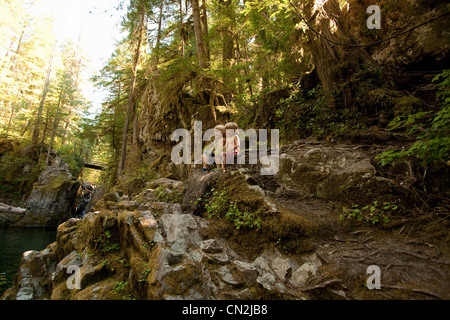 Deux garçons assis sur les rochers en forêt Banque D'Images