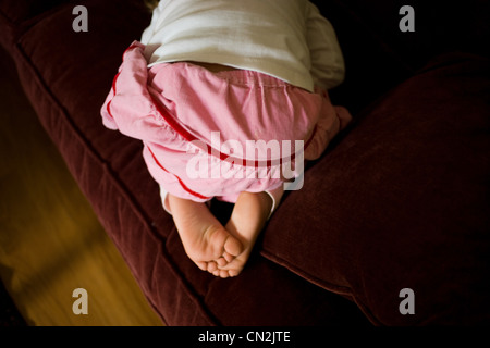 Jeune fille à genoux sur canapé Banque D'Images