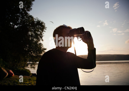 Man looking through binoculars at sunset Banque D'Images