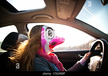 Femme au volant voiture portant un masque de clown Banque D'Images