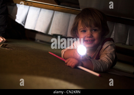 Jeune fille jouant avec une torche sous bed Banque D'Images