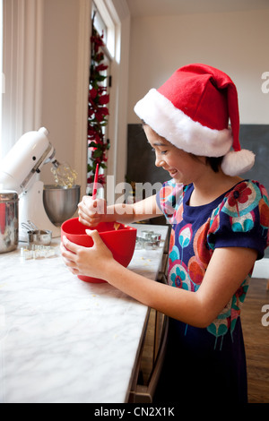 Girl in santa hat making christmas cookies Banque D'Images