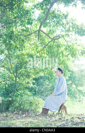 Jeune femme assise sur la selle d'arbres Banque D'Images