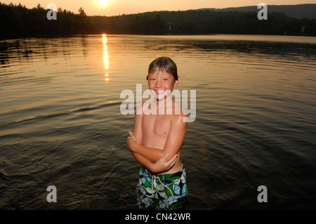Jeune garçon debout dans le lac au coucher du soleil, du lac des Neiges, Québec Banque D'Images
