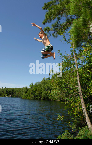 Jeune garçon sautant d'une falaise dans le lac, du lac des Neiges, Québec Banque D'Images