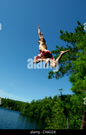 Teenage Boy Jumping off Cliff, lac des Neiges, Québec Banque D'Images